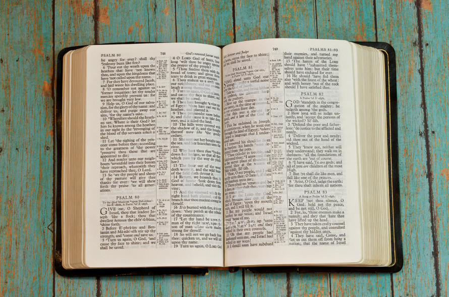 pages of a Bible opened to Psalms on a weathered teal wood table 