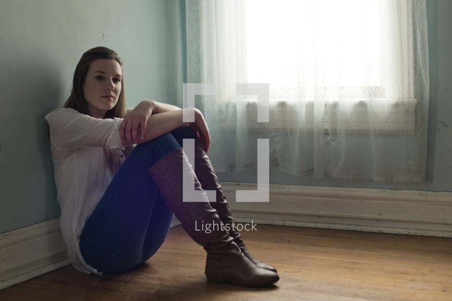 teen girl sitting alone in an empty room 