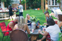 people eating around a table at an outdoor party 