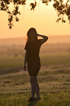 a young woman standing outdoors at sunset 