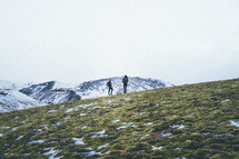 two men hiking up a mountain in winter 