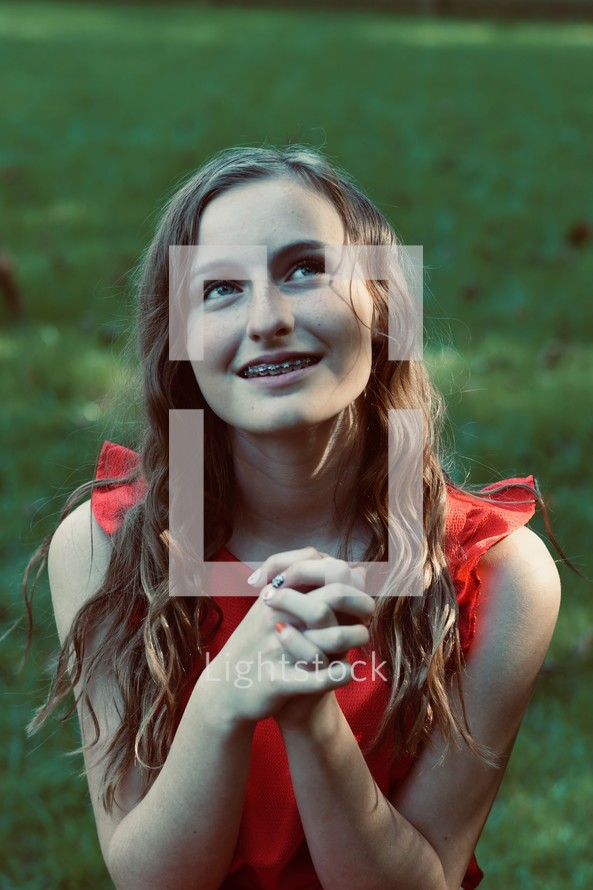teen girl with braces looking up to God with praying hands 