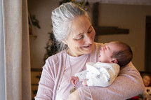 Grandmother holding yawning newborn baby and smiling