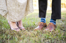 feet of a couple standing in grass 