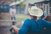 a man in a cowboy hat sitting in a backyard