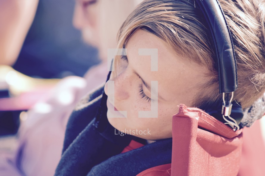 a sleepy child listening to headphones 