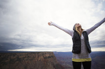 woman standing on a mountain top with raised hands 