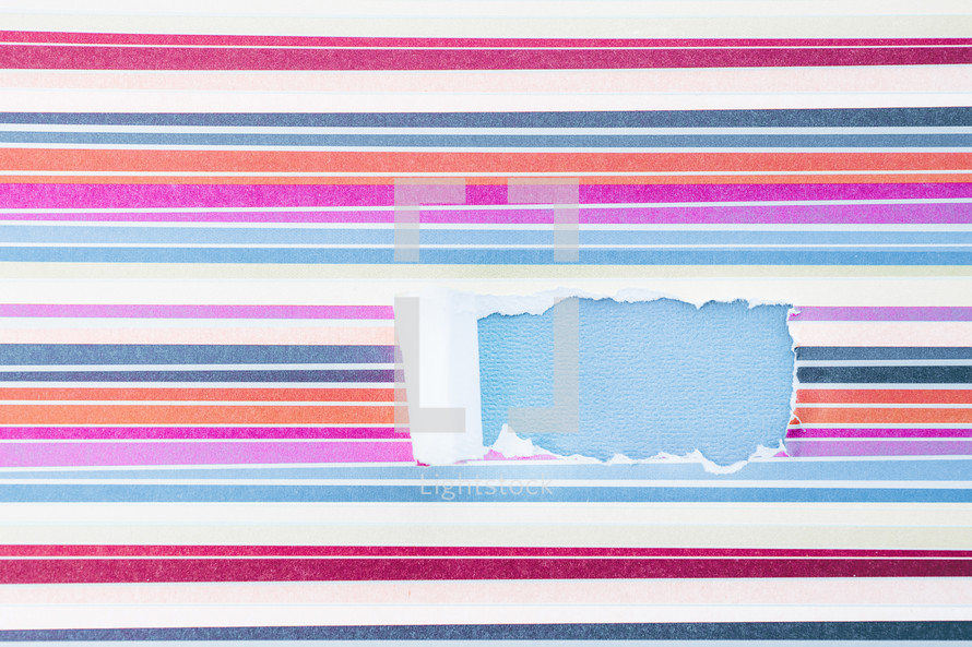 torn striped paper revealing blue underneath 