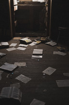 books and pages on the floor of an abandoned house 