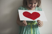 little girl holding a heart painting 
