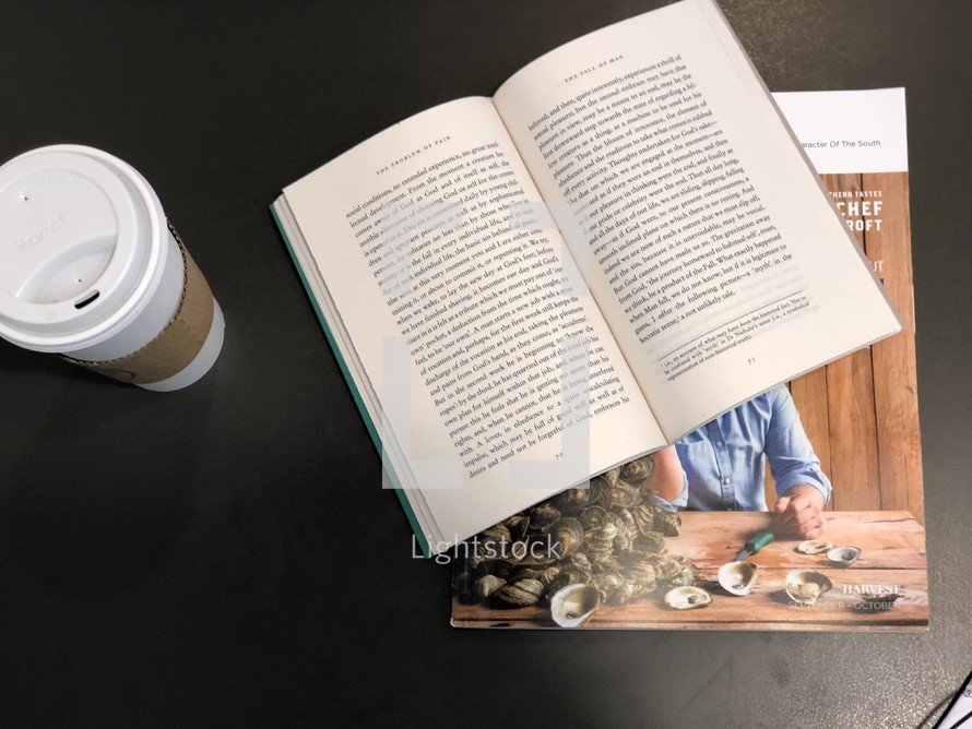 pages of an open book and coffee cup on a table 