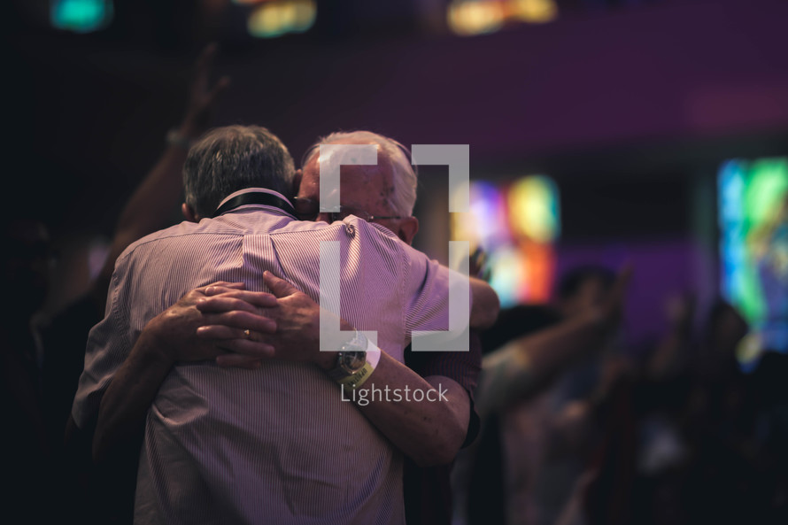 elderly men hugging at a worship service 