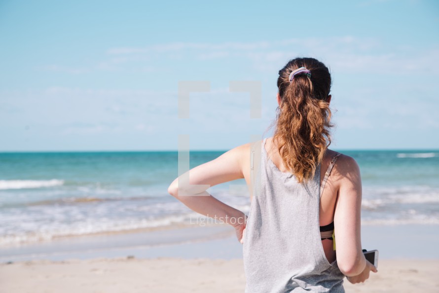 woman walking on a beach holding a camera 