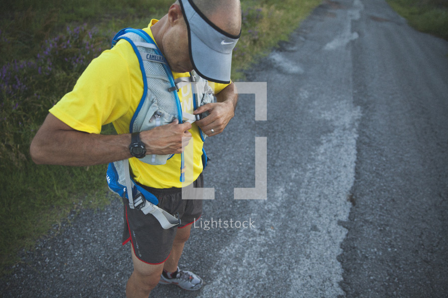 A runner putting on a hydration vest. 