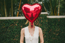 woman holding a heart shaped helium balloon 