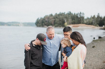 a family praying together on a lake shore 