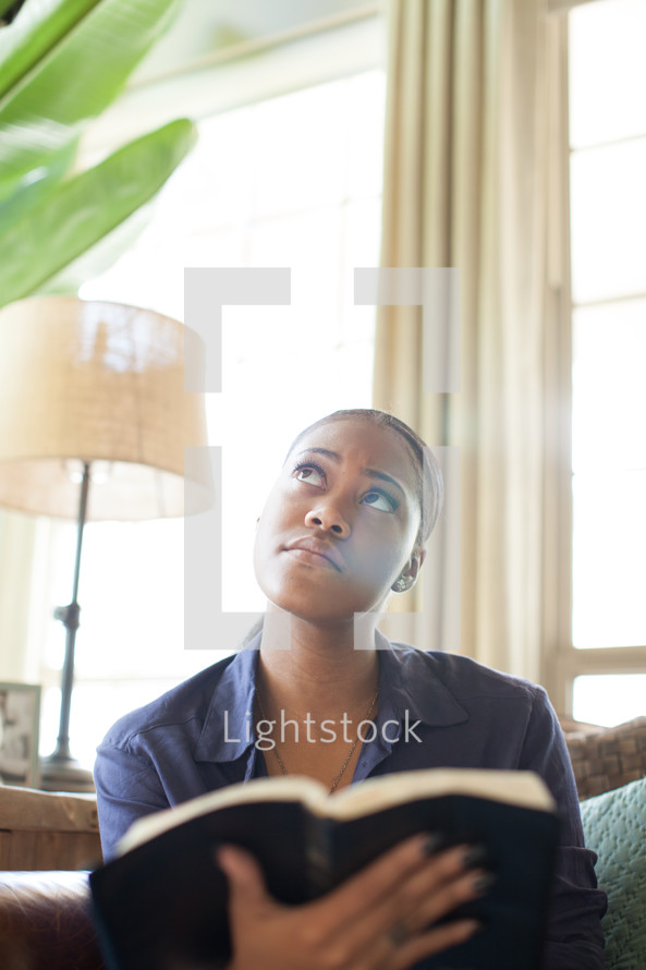 African-American woman reading a Bible in her living room 