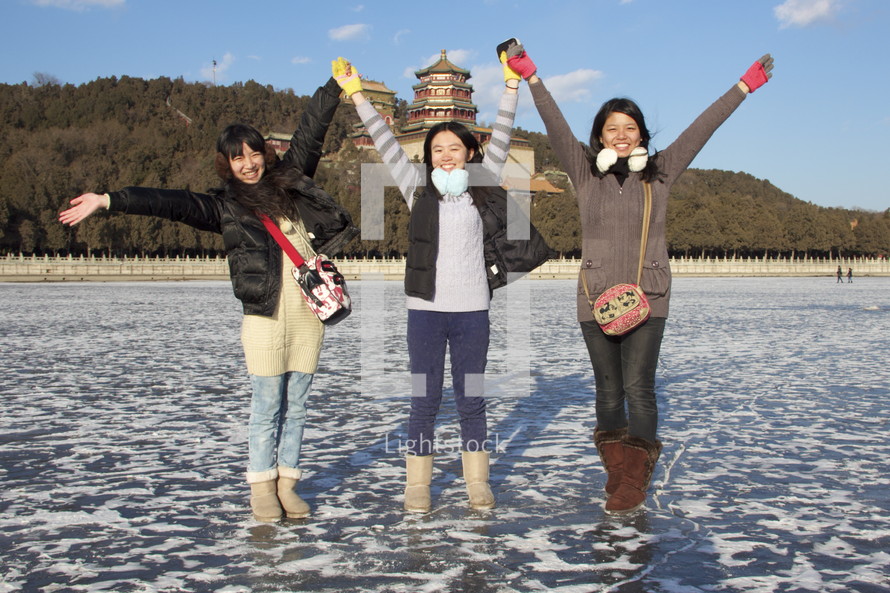 joyous young women standing on a frozen lake in China