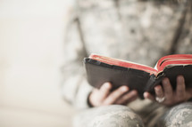Female soldier reading through an old Bible.