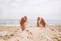 Male feet in sand on beach. Sunbathing, summer vacation, tan concept. Happy tourist rests near sea or ocean. High quality photo
