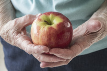 elderly woman holding an apple