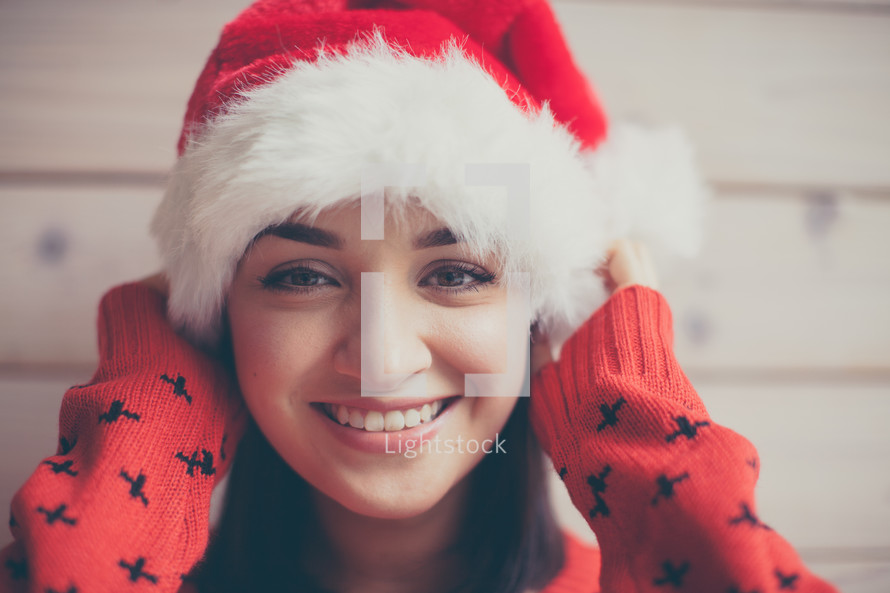 head shot of a woman in a Santa hat and Christmas sweater 