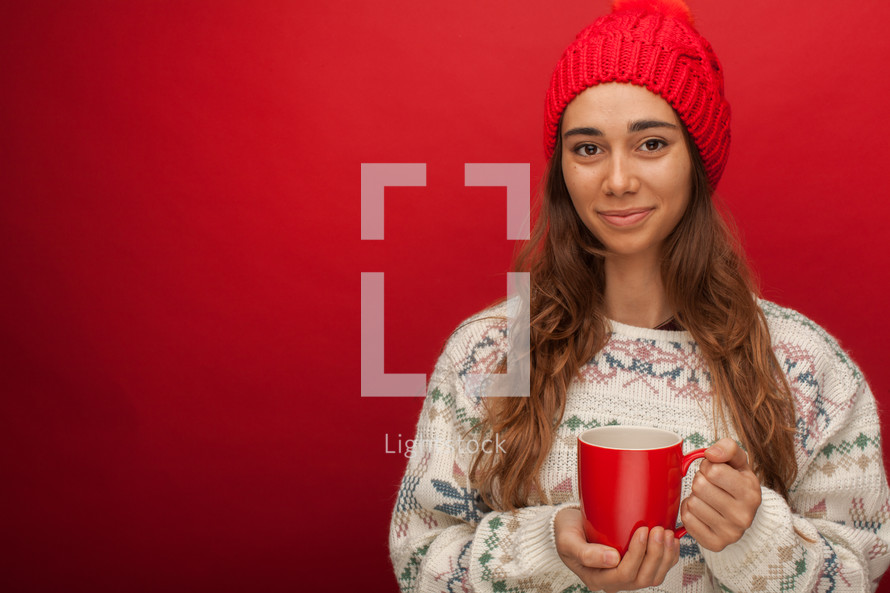 a woman in a sweater holding a mug 