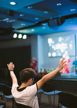 a young man alone in an audience with raised hands 
