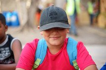 a child in a hat with a book bag over his shoulders 