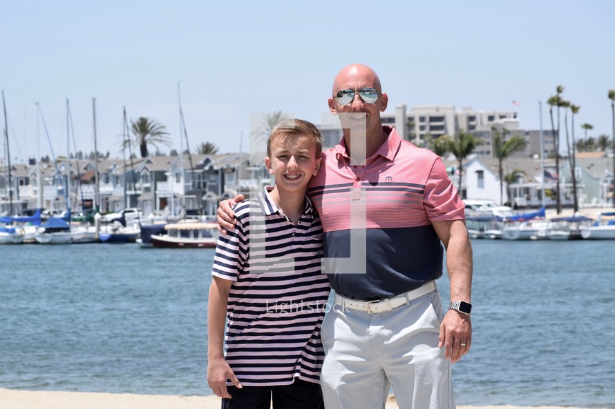 father and son standing in front of a marina 