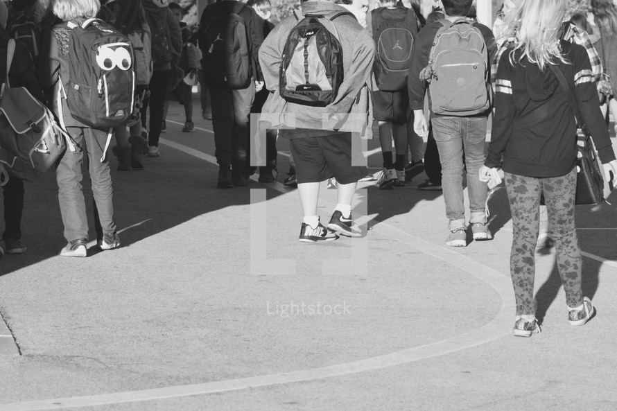 a group of kids walking home after school in black and white 