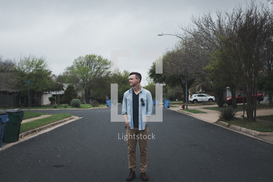man standing in the middle of a neighborhood street 