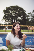 a woman at a dinner party next to a swimming pool