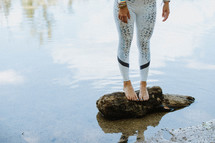 woman standing on a log in a pond 