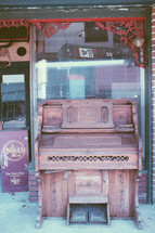 old piano in front of an antique store 