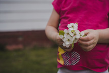 toddler girl holding picked flowers 