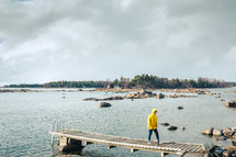 woman in a yellow raincoat walking on a pier 