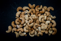 lots of cashews scattered on black background with place for text
