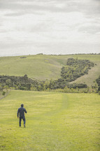 a man walking in a field of green grass 