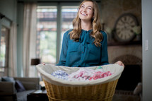 A smiling woman holding a basket of laundry.