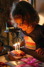 girl child blowing out a birthday cake 