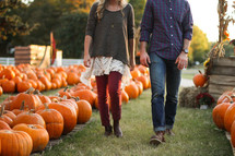 a couple walking through a pumpkin patch 
