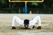 a man on a football field doing pushups 