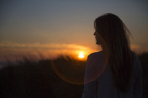 A woman facing the sunset.