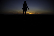 Silhouette of a woman in front of a sunset.