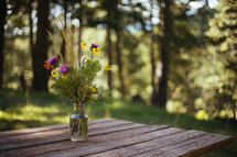 wildflowers in a vases on a picnic table 