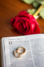 red rose and wedding bands on the pages of a Bible 