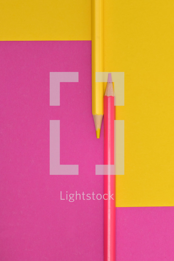 Abstract yellow and pink crayons on the same paper background