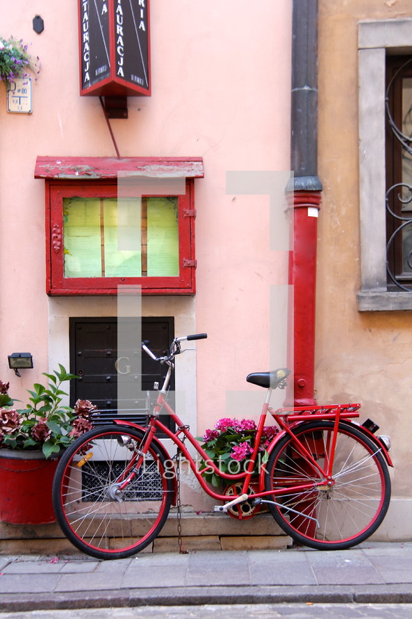 Red ladies bicycle and flower pots outside pink painted shop