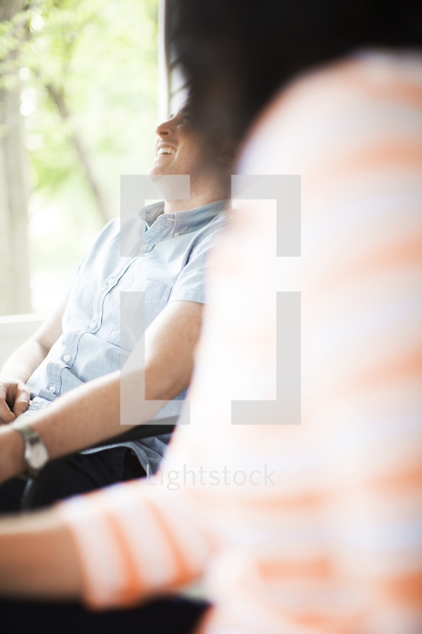 man and woman sitting on a front porch talking 